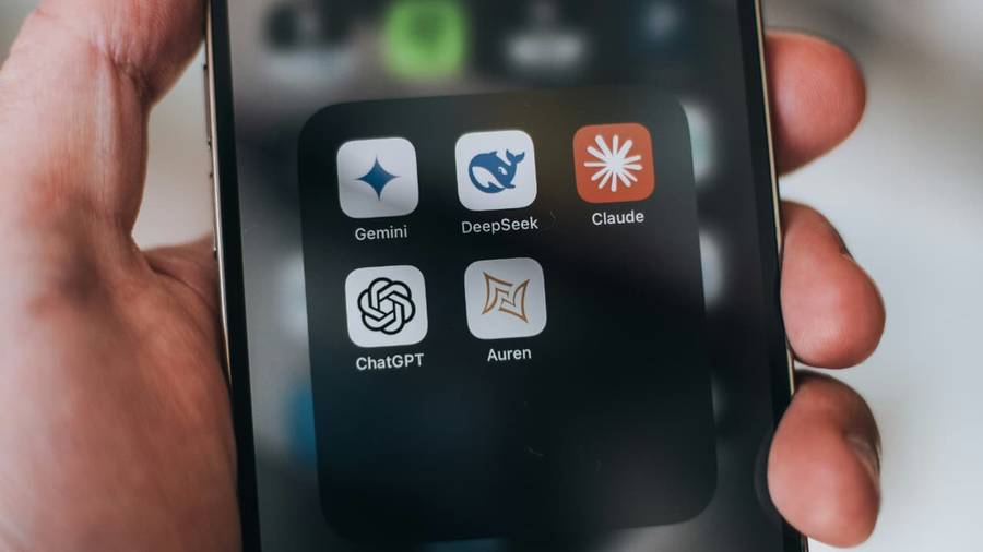 A hand holding a phone showing a folder of AI assistant apps